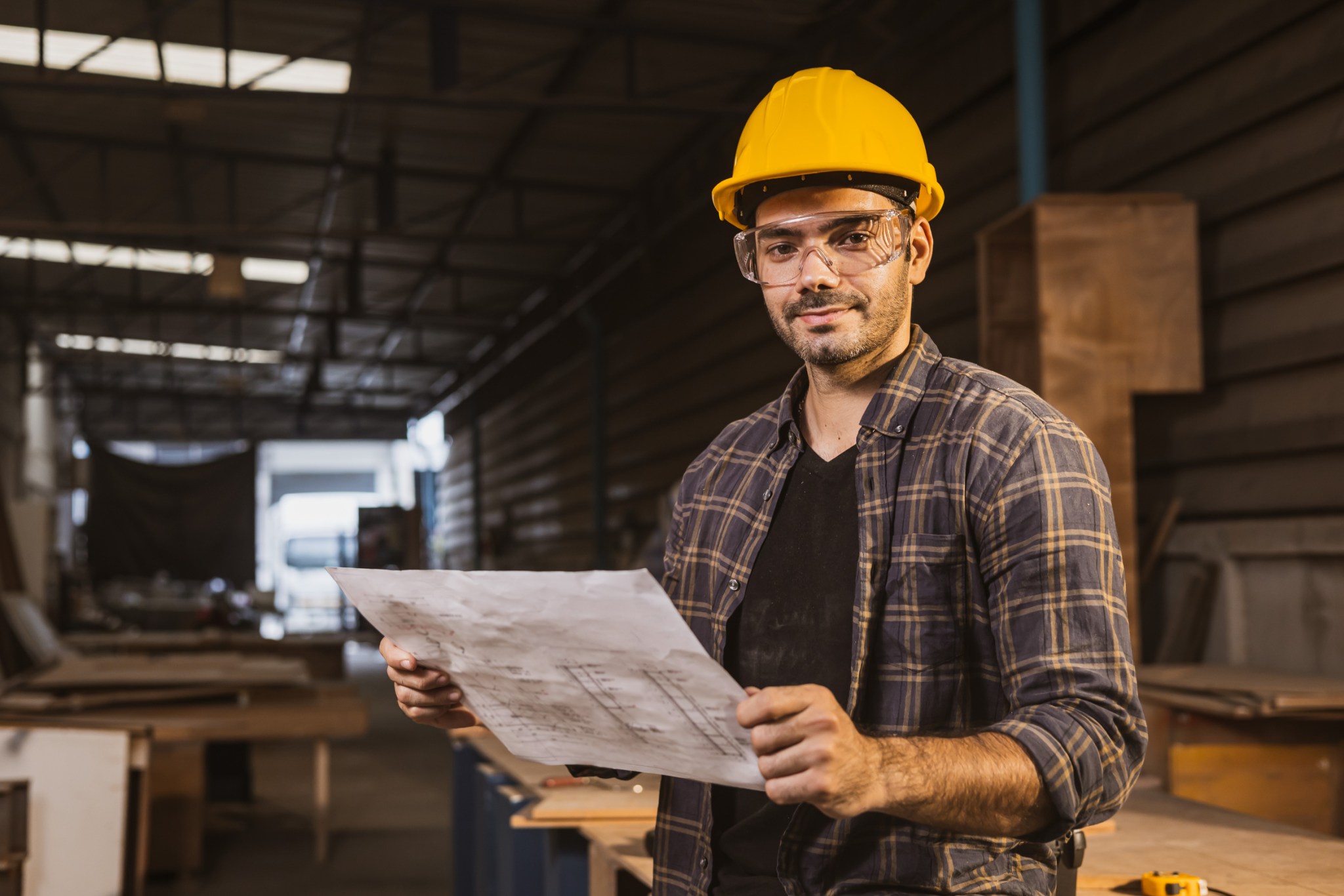 Owner of a contracting business holding project plans in his workshop